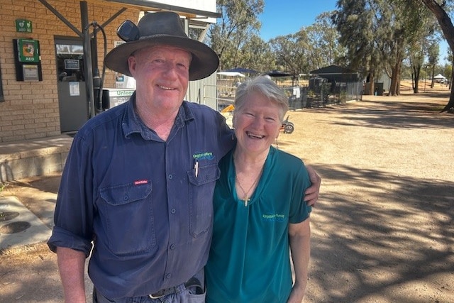 A man wearing an akubra and a woman both smiling, standing next to each other in front of a building in the Riverland.