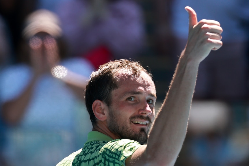 Daniil medvedev gives a thumbs up as he smiles over his shoulder at the Australian Open.