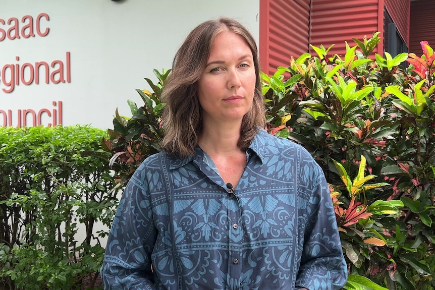 A serious looking woman stands in front of the Isaac council building.