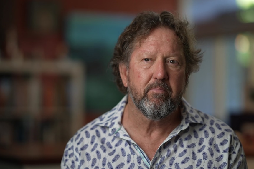 A photo of a man in a white collared shirt with a blurry background