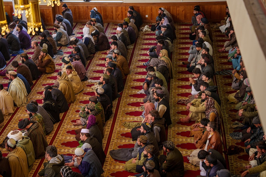 A group of Afghans sit on the floor of a mosque for prayers in Kabul.