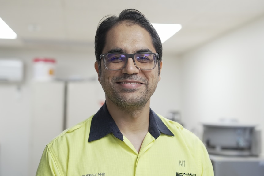 A man with dark hair and glasses, smiling at the camera.