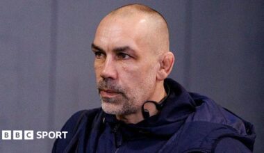 Alex Sanderson looking straight ahead with a grey wall behind him