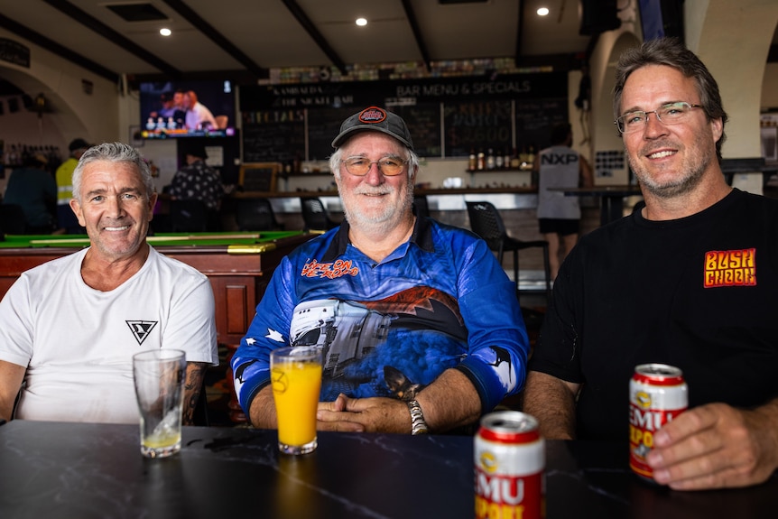 Three men sitting at a table in a bar at local pub.  