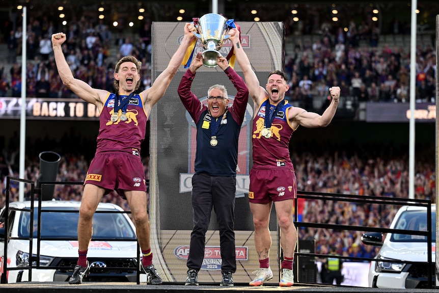 Chris Fagan and Lachie Neale holding up the AFL premiership trophy
