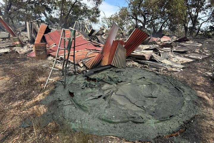 a damaged structure and a circular pit of ash on the ground