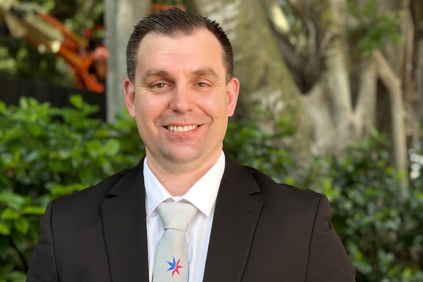 A man in a suit and tie smiling at the camera