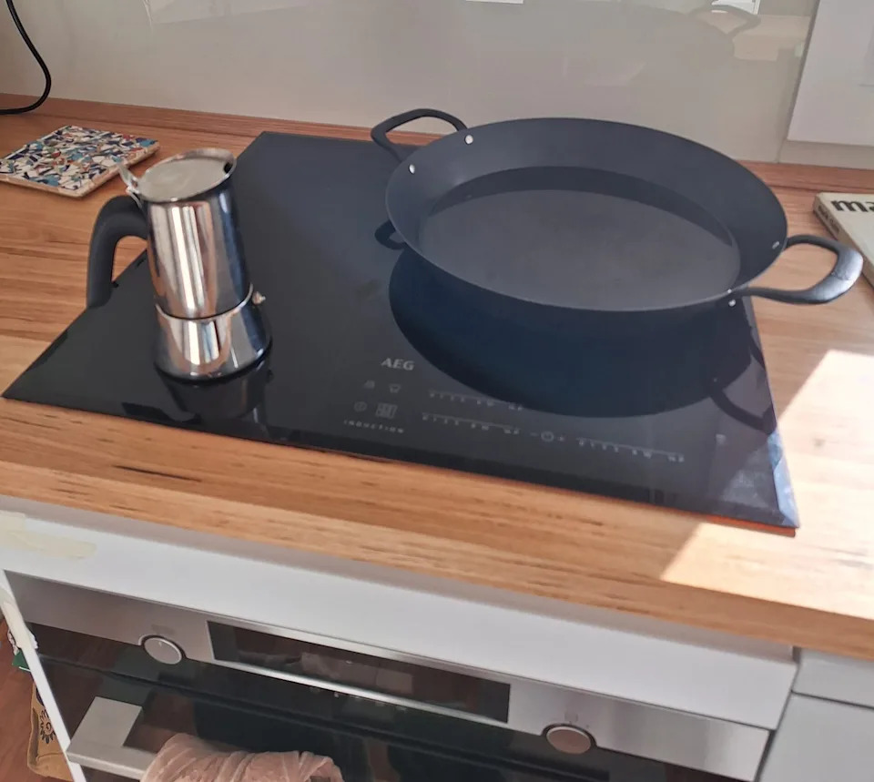 An induction cooktop with a coffee pot and wok placed on top. 