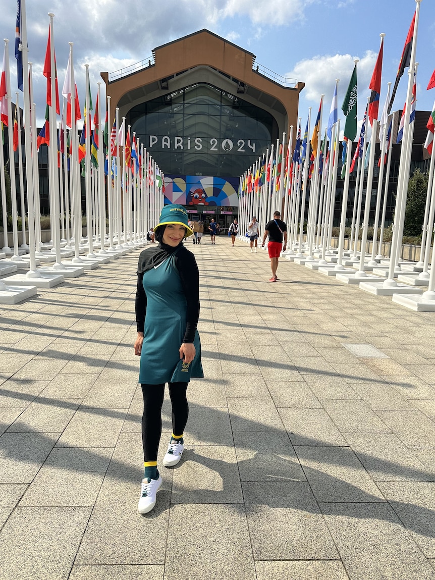 Tina Rahimi walks on path, Paris 2024 sign on building behind her.