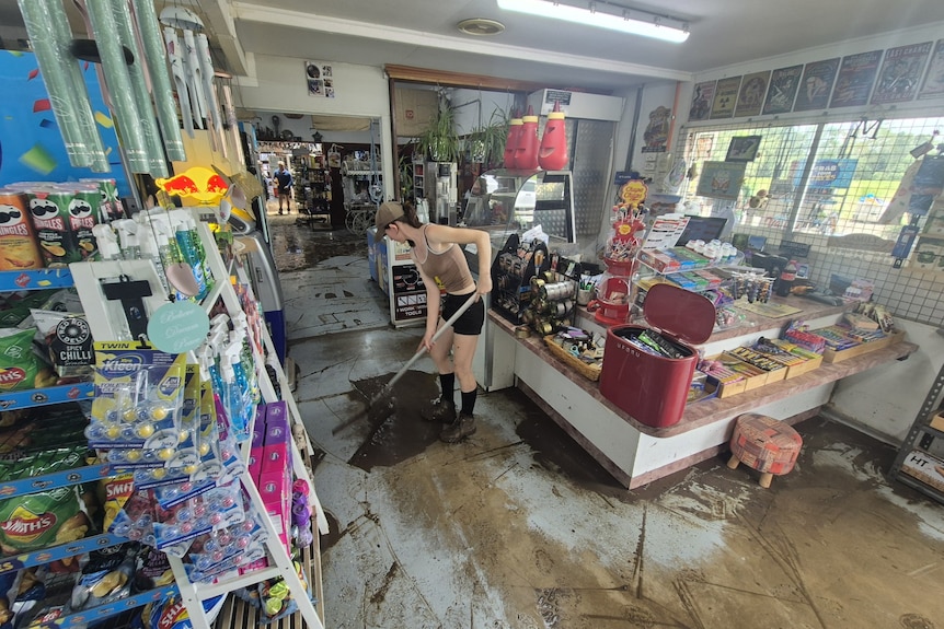 A woman sweeps up mud in a shop.