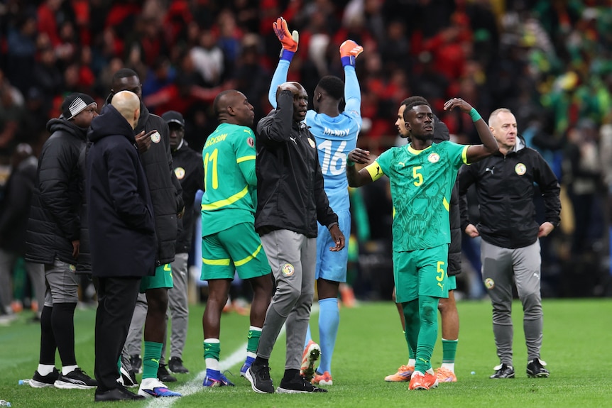 Senegal players and manager beckon to players to leave the field 