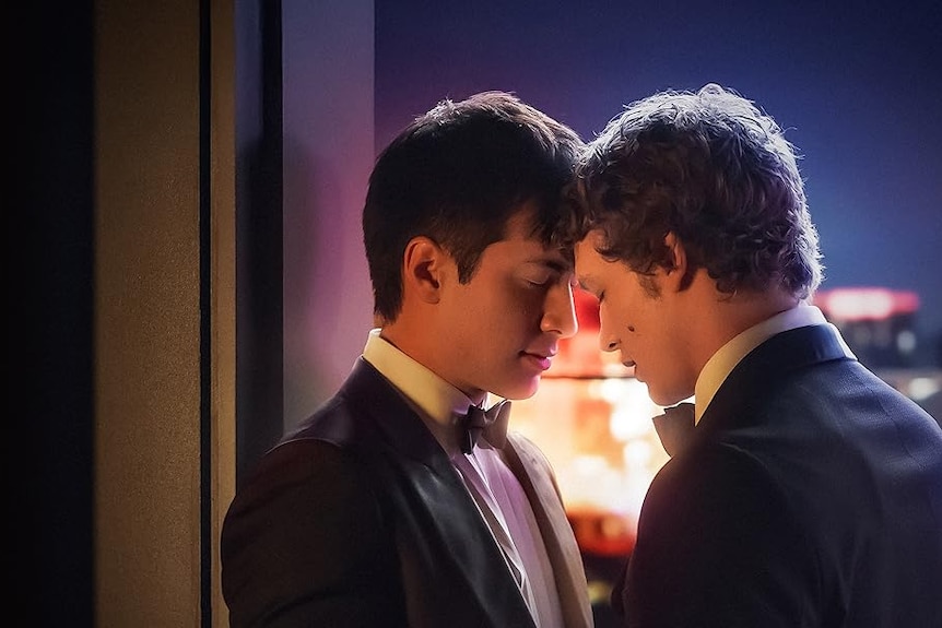 Screenshot of the two main characters in Heated Rivalry with heads resting on each other, dressed in tuxedos