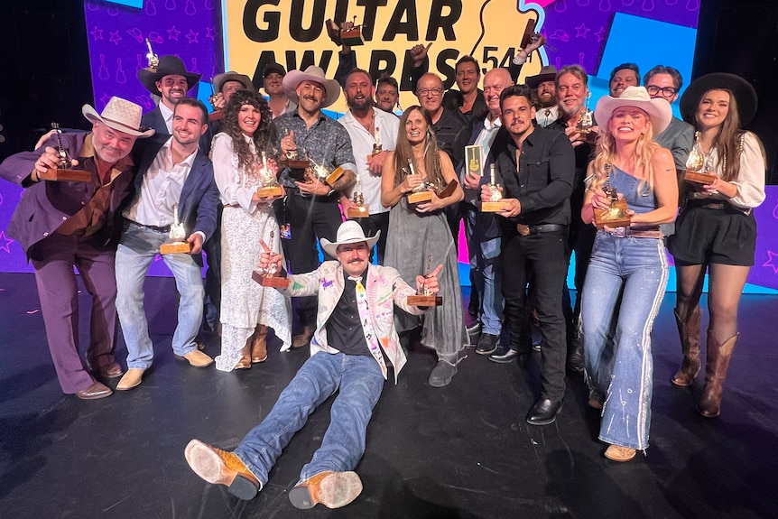 A group of people on a stage holding Golden Guitar Awards