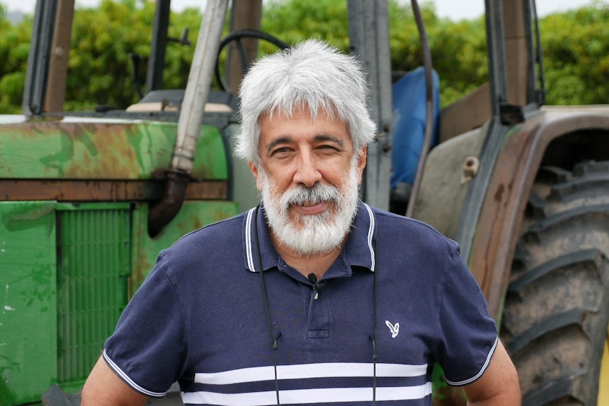 A mid shot of a man standing in front of a tractor. 