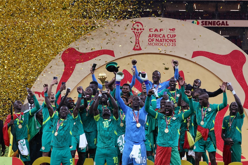 Senegal players celebrate with the trophy under falling confetti