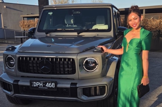 Chanthy is a pretty young Asian woman in a green formal dress stands next to a car.