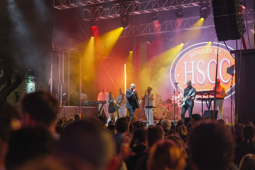 A band playing up on a stage with colourful lights.