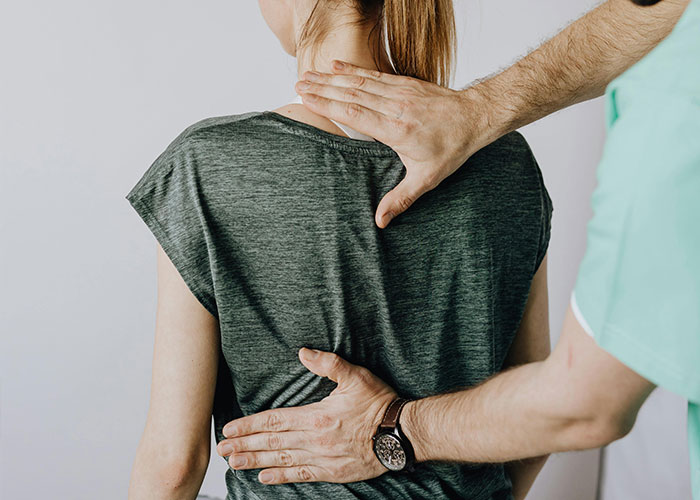 Medical professional examining patient's back with hands, illustrating the worst things said to patients in healthcare.