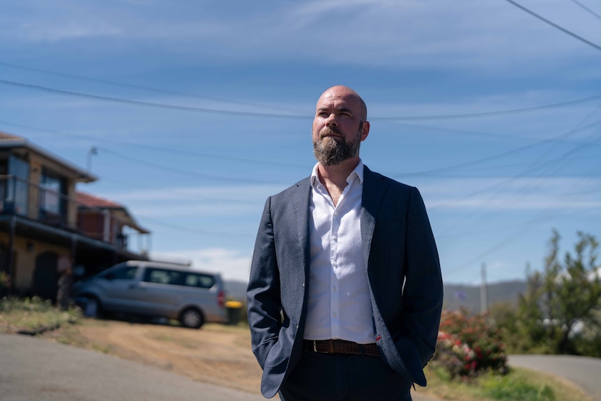 Man stands on a suburban street looking out into the distance
