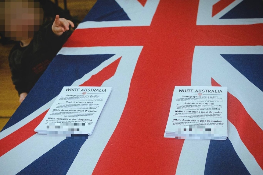 Two piles of flyers with the heading "White Australia" on top of a Union Jack flag being used as a tablecloth.
