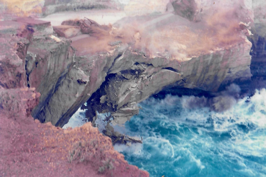 A massive piece of rock falls into the ocean from a cliff