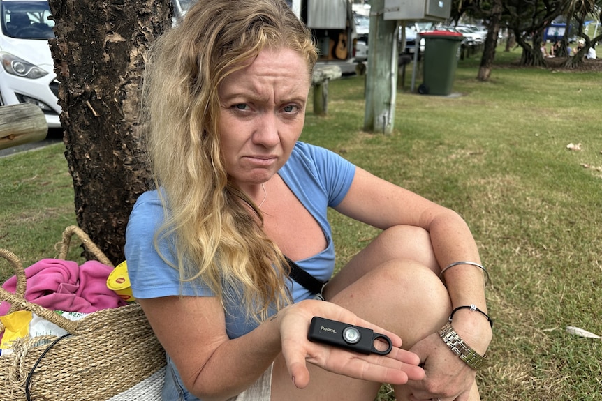 woman holding small black device in hand