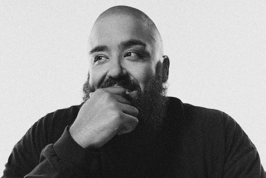 A black and white image of Adrian Eagle. He has a moustache and beard and wears a black hoodie.