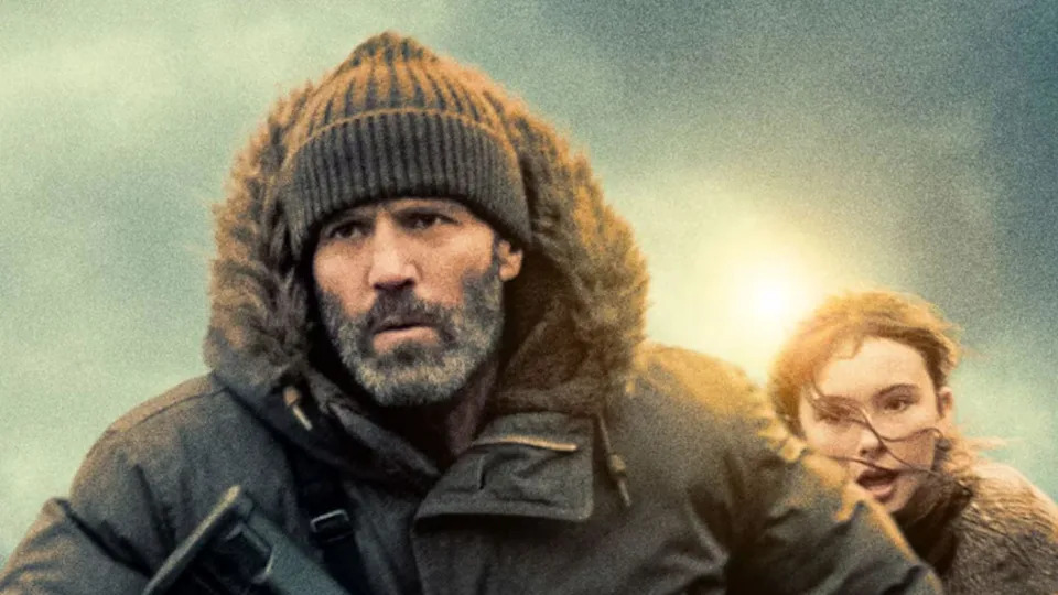 Jason Statham wearing a hat and coat with a young girl behind him 