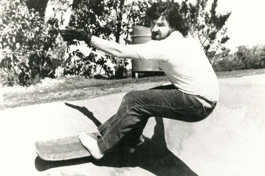 A barefoot man rides a bend on a skateboard. 