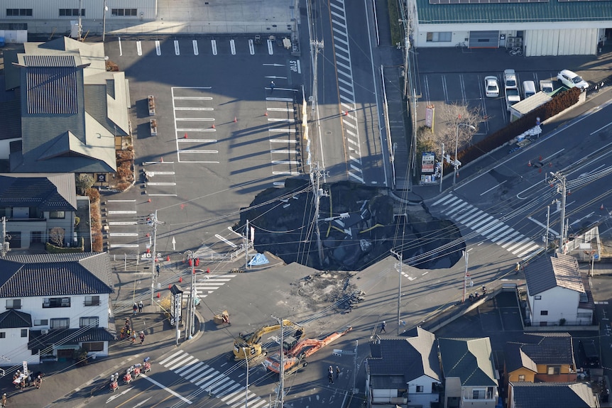 An aerial view shows a large sinkhole that swallowed a truck and a man