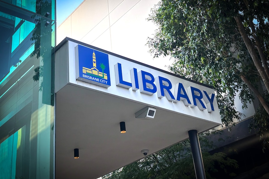 A sign for a library on the building nextto the Brisbane City Council logo showing town hall.