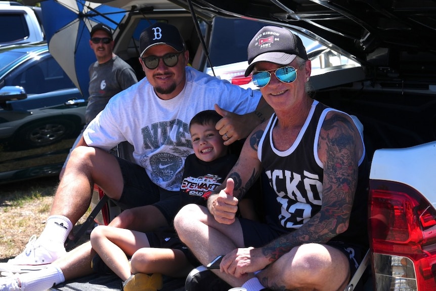 Two adults and a child attend a car festival.