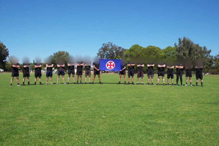 A group of men with blurred photos holding a flag with a symbol of a cross on it. 