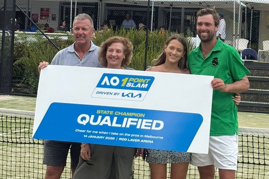 Four people hold up a sign reading "QUALIFIED" while standing at the net on a tennis court.