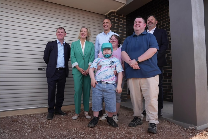 a group of people standing in front of a house and roller door