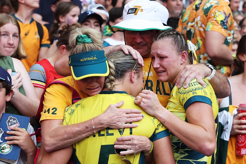 Teagan and Maddison Levi are comforted by their family after losing a rugby sevens match