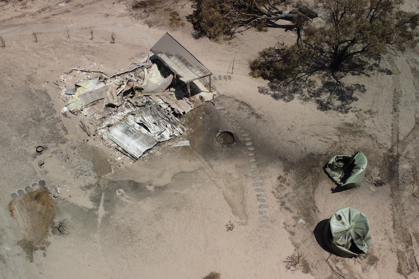 view from above burned land with building debris and ruined water tanks.