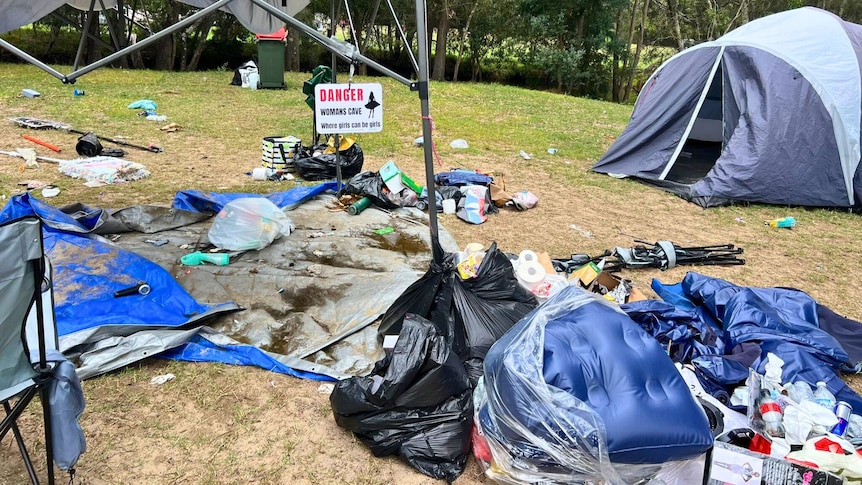 piles of rubbish, tents and misc camping equipment on a large patch of grass