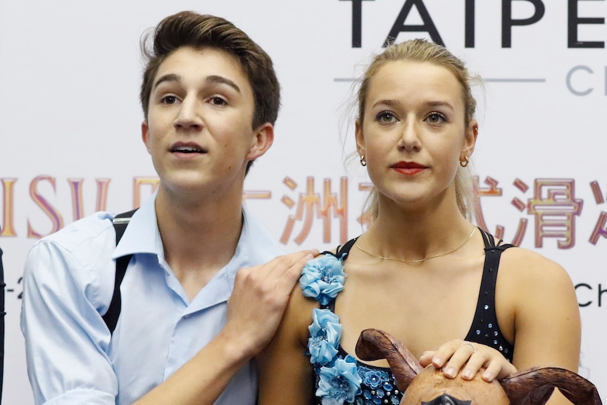 A man and woman look straight ahead as they wait for their scores from judges.