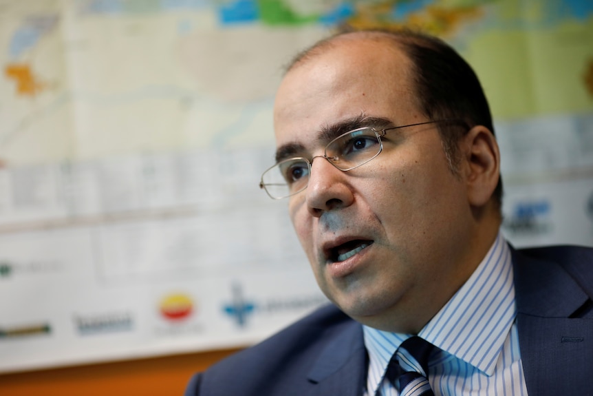 A man wearing glasses and a uit and tie speaks.