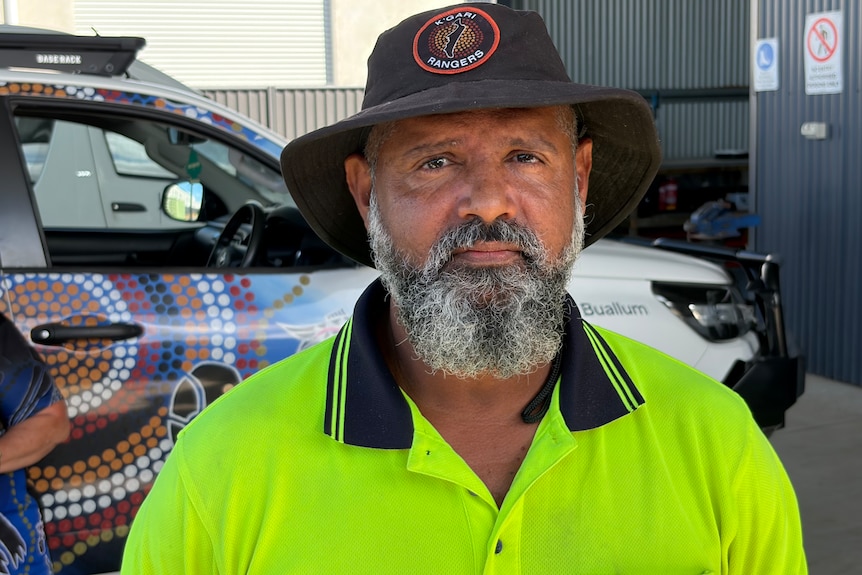 A man in a high-vis shirt standing in front of a ute.