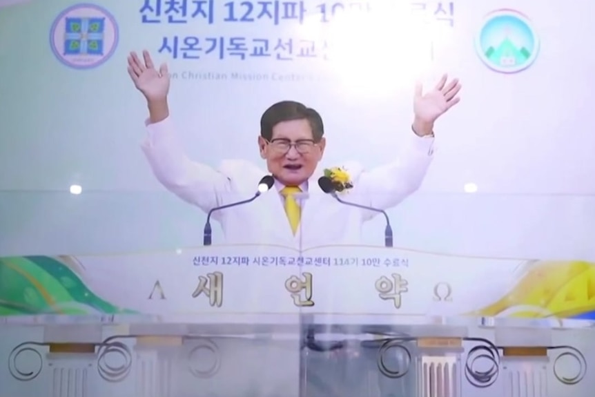 A poster of a man in a white suit in front of a podium with his arms raised.