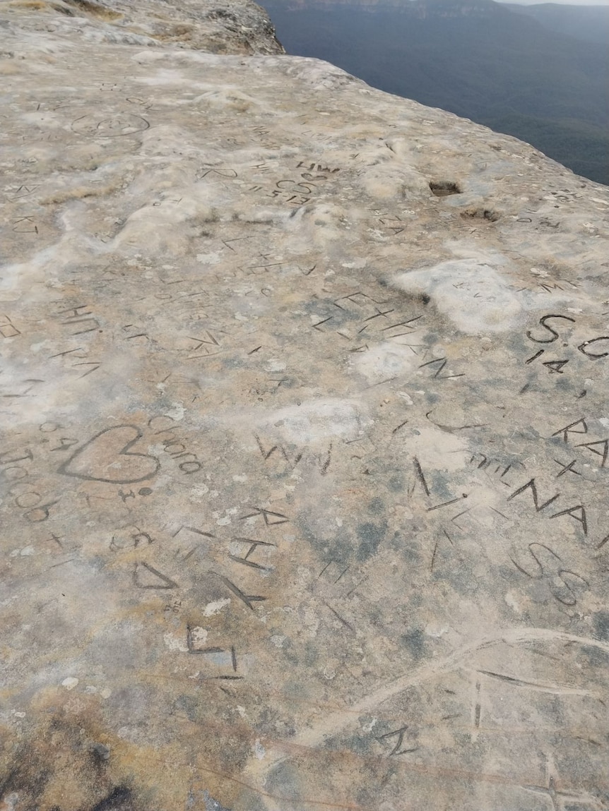Names and symbols carved into sandstone.