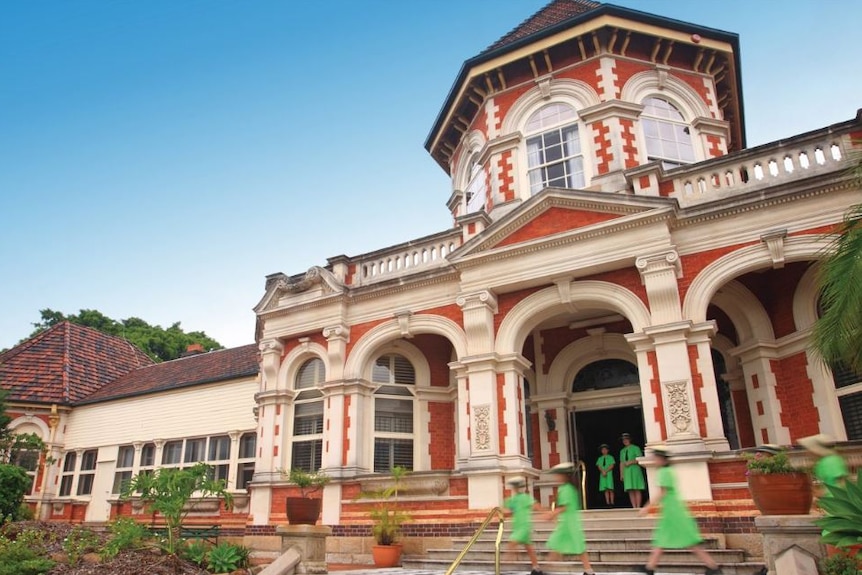 An exterior image of Somerville House girls' boarding school,  red brick in 1920's building with girls walking in front.