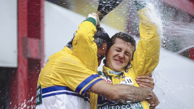 Michael Schumacher from Germany, driver of the #19 Camel Benetton Ford Benetton B192 Ford HB V8 celebrates on the podium by pouring the victory bottle of Moet et Chandon over himself and Flavio Briatore after claiming his first Grand Prix victory at the Formula One Belgian Grand Prix on 30th August 1992 at the Circuit National de Francorchamps in Spa Francorchamps, Belgium. (Photo by Pascal Rondeau/Allsport/Getty Images)