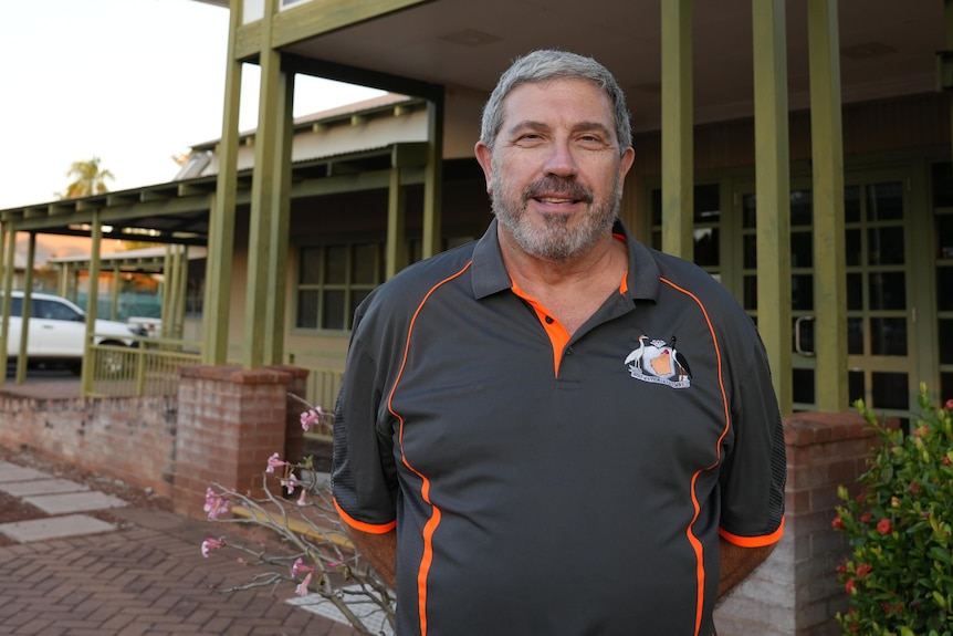 middle-aged white man with a grey polo posing in front of the shire building