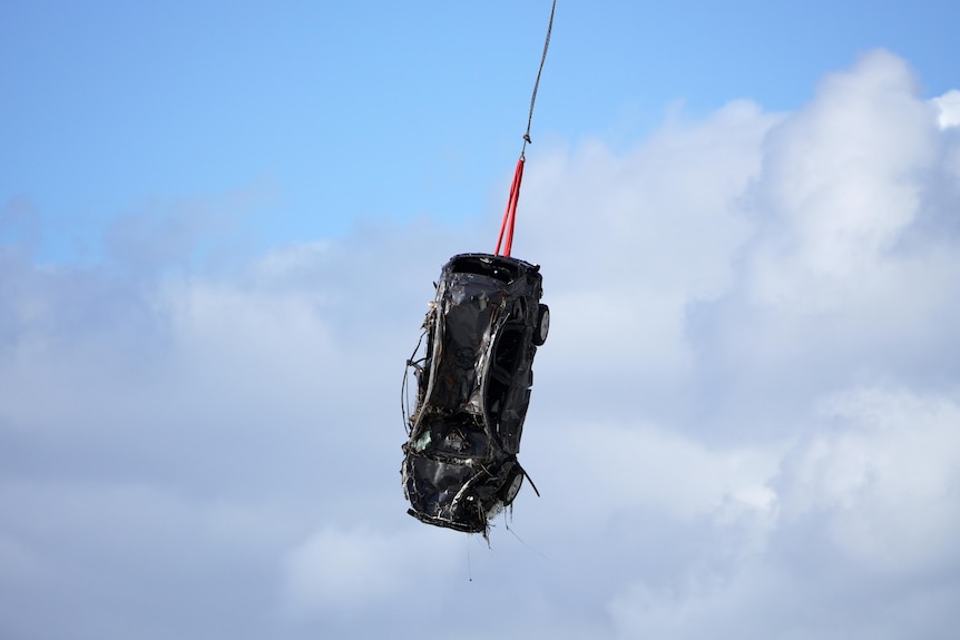 A car being winched from the sea by a helicopter along the Great Ocean Road.