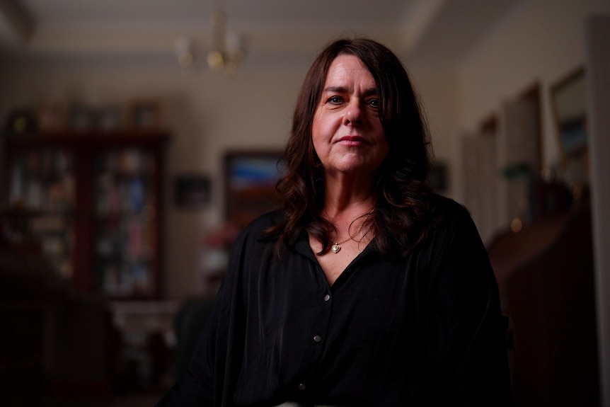 A woman with long dark hair standing inside a house.