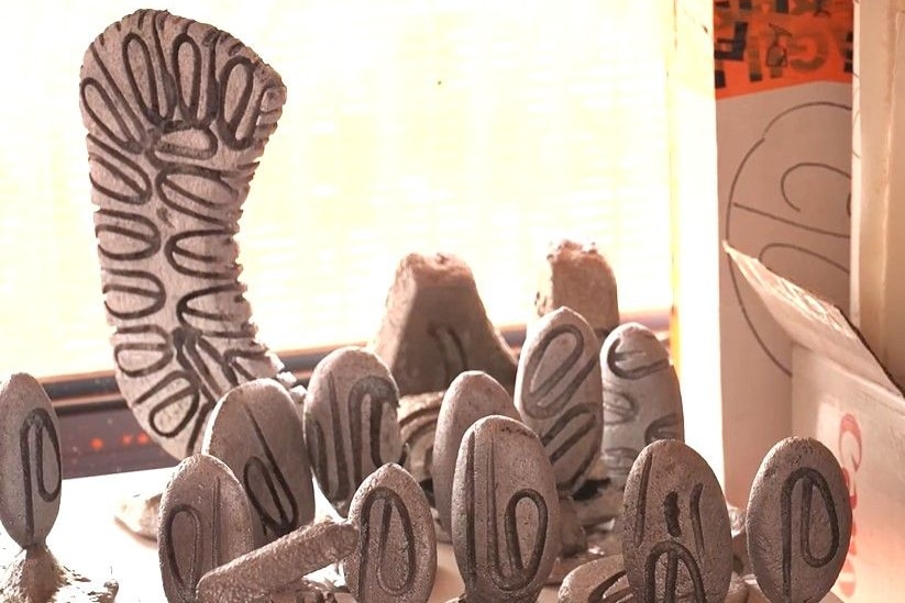 Numerous, small, carved metal sculptures on a table with a taller one in the background.