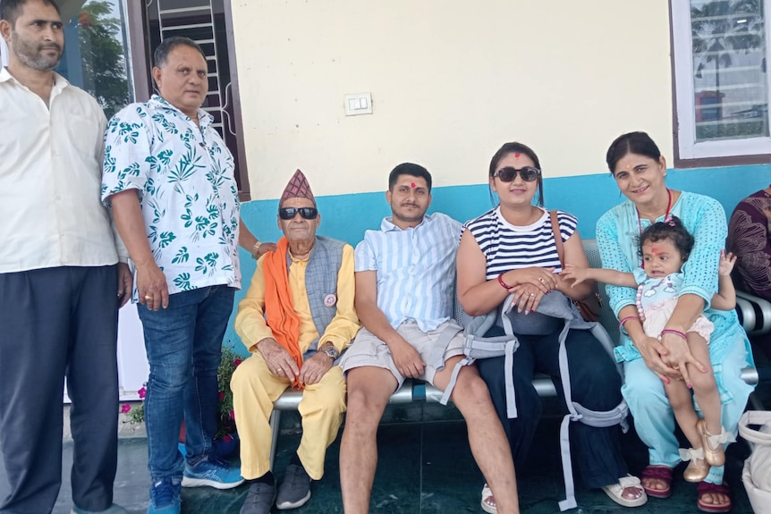 A man of Nepalese descent sitting with his wife, daughter and other family members 